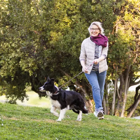 Flotte Dame geht mit Hund im Park spazieren